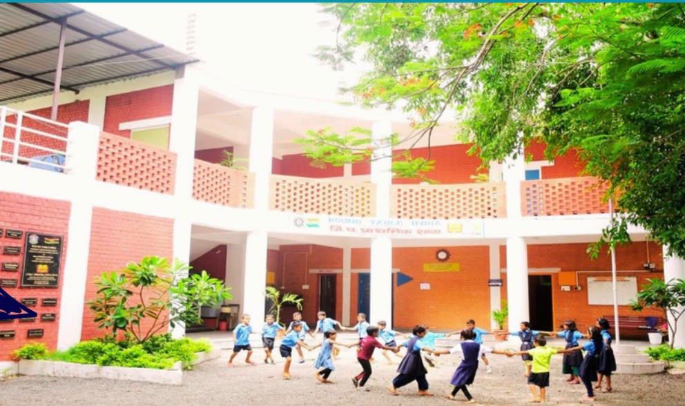 Children playing in a ring on the ground at the Round Table India school in Sukali, both floors complete